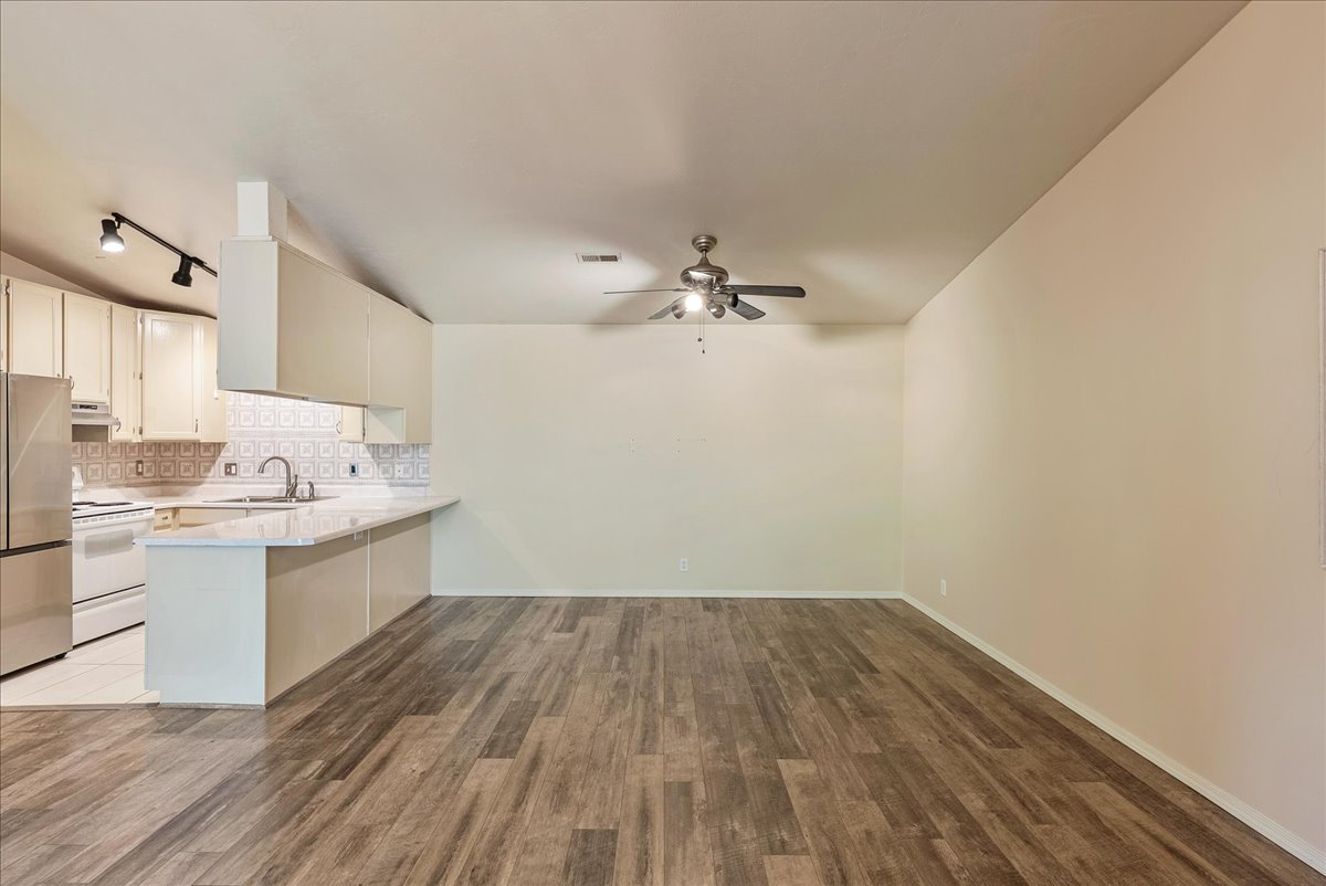 Kitchen with a peninsula, decorative backsplash, freestanding refrigerator, dark wood finished floors, and electric stove