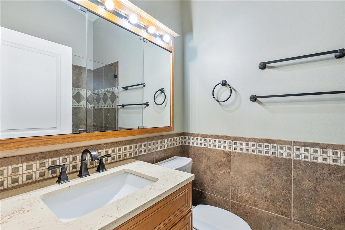 Bathroom featuring vanity, a tile shower, and tile walls