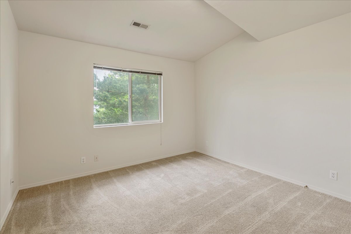 Unfurnished room featuring light carpet and lofted ceiling