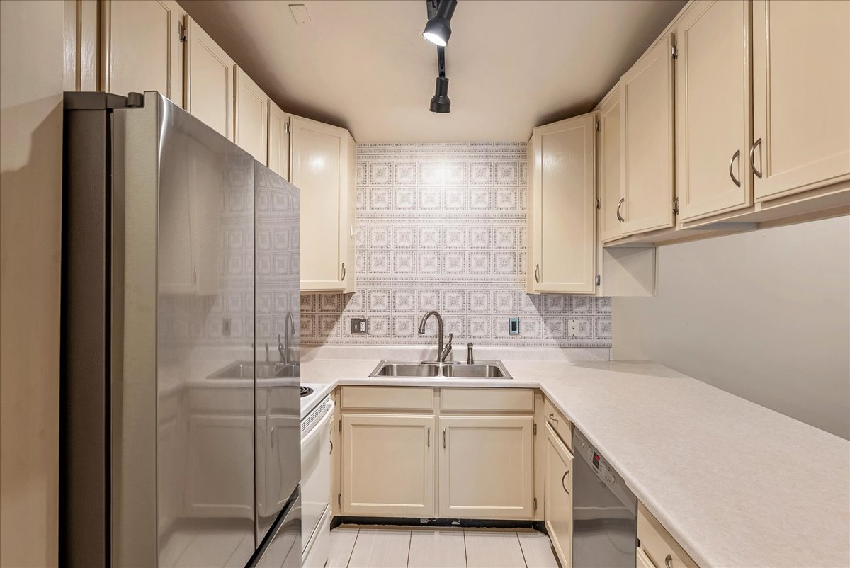 Kitchen featuring stainless steel appliances, light countertops, decorative backsplash, and cream cabinetry