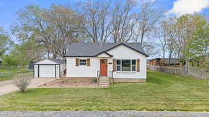 Bungalow-style home with concrete driveway, a garage, and front lawn