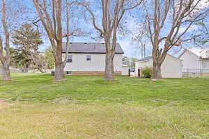 Back of house with grassy lawn area and trees