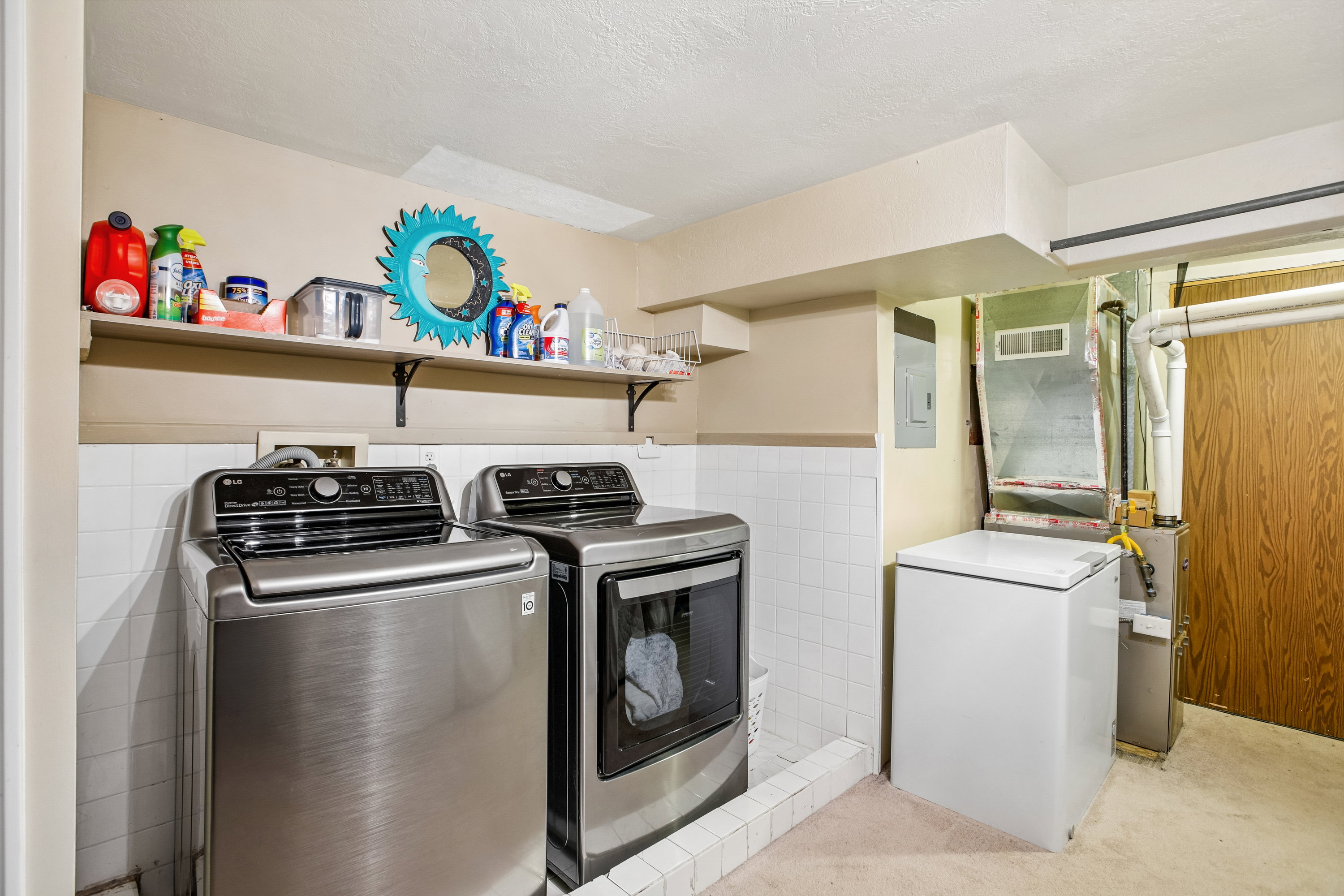 Laundry area featuring a wainscoted wall, electric panel, separate washer and dryer, tile walls, and heating unit