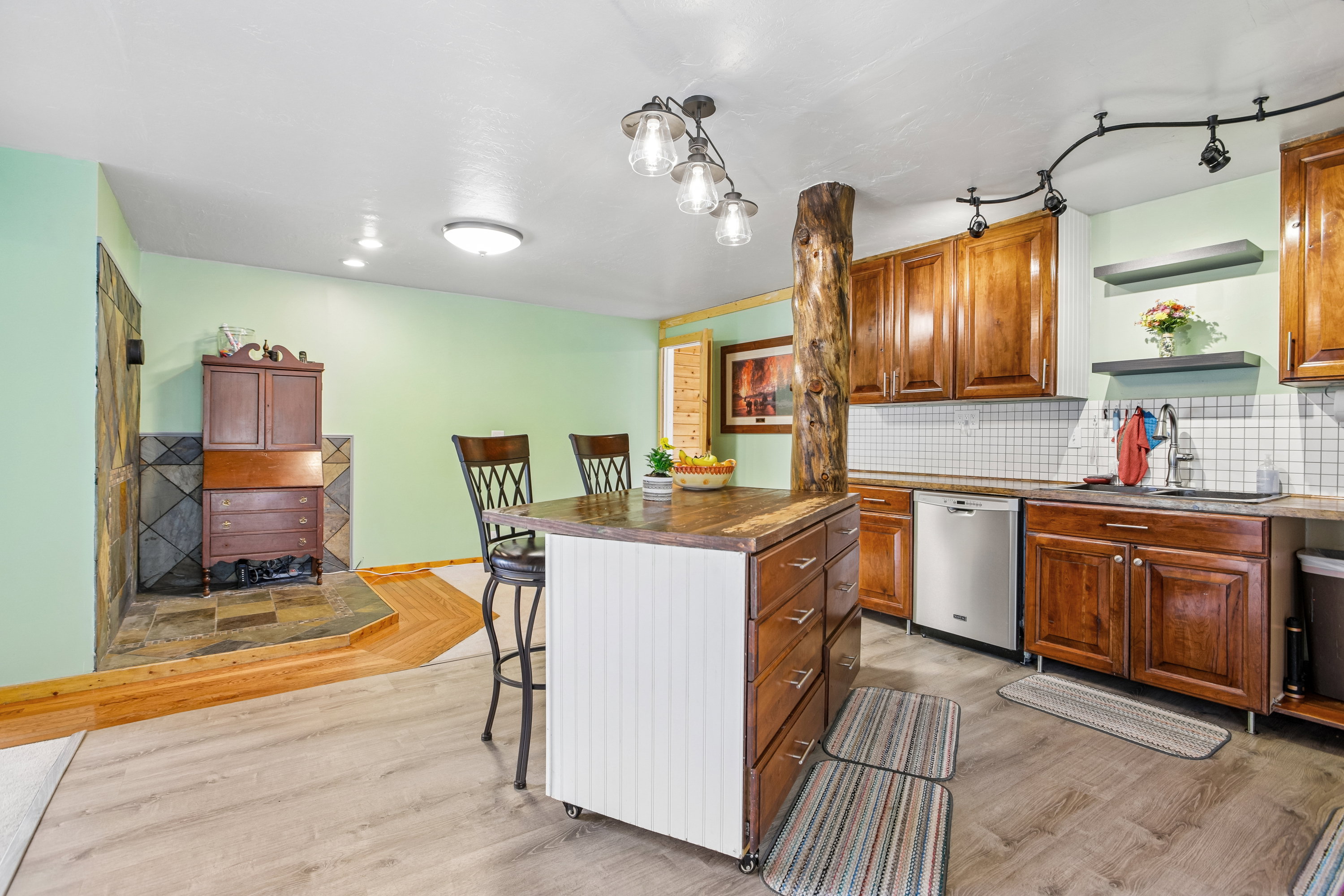 Kitchen featuring a breakfast bar, decorative backsplash, dishwasher, and light wood-type flooring