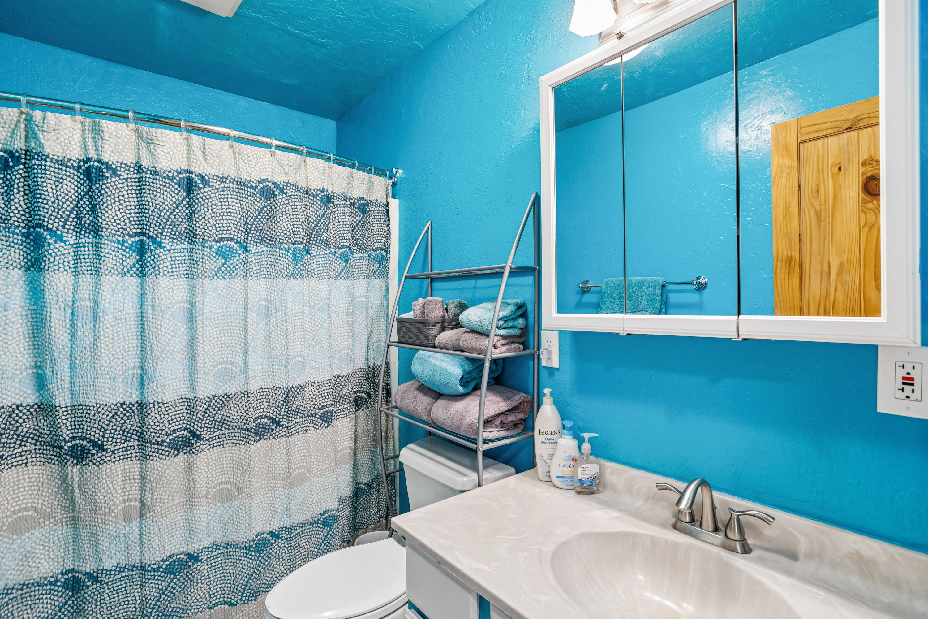 Full bathroom featuring a textured wall, vanity, and a shower with shower curtain