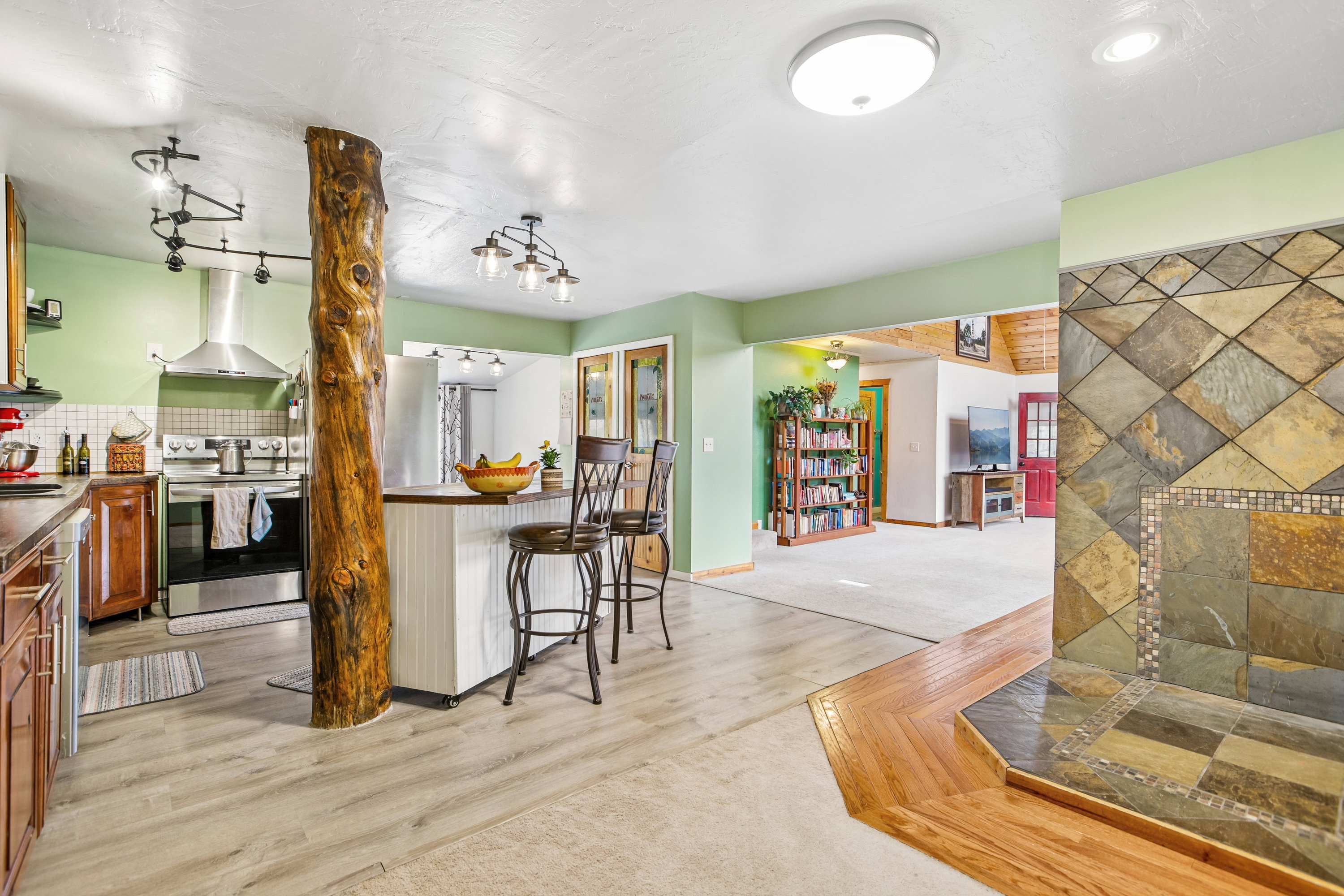 Kitchen with a kitchen bar, stainless steel appliances, dark countertops, light carpet, and light wood-style flooring