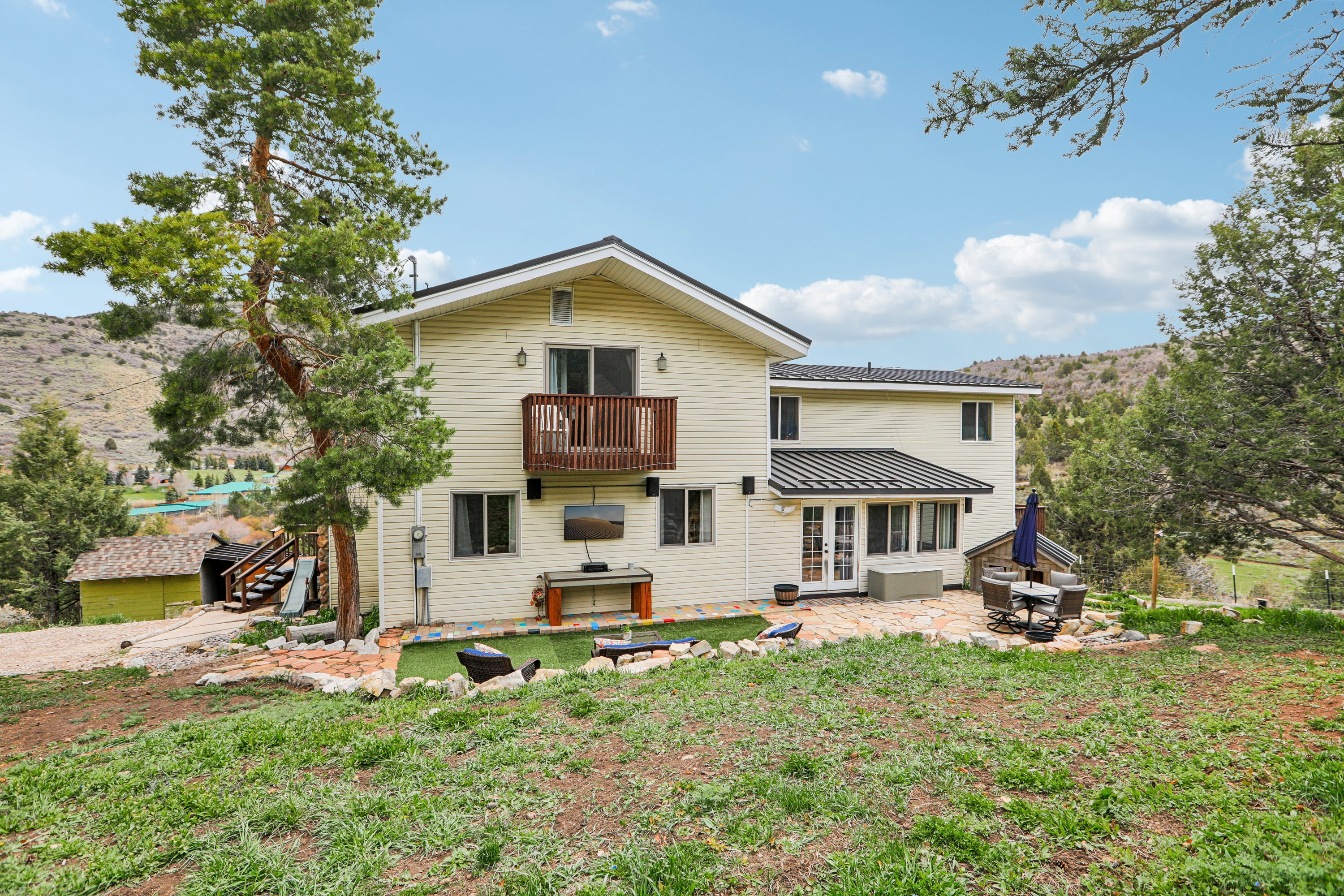 Back of house with french doors, a patio, a sunroom, a standing seam roof, and a mountain view