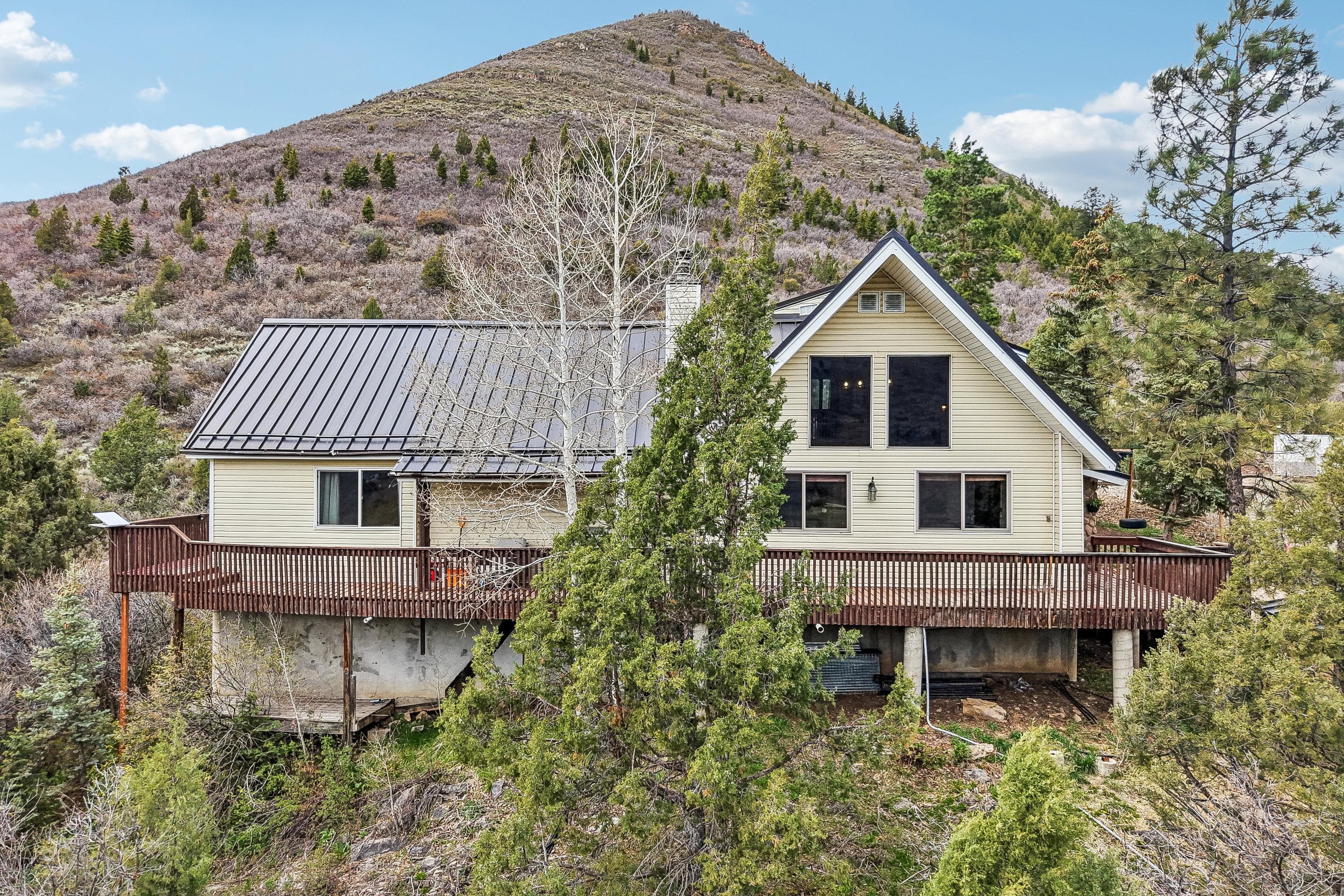 Rear view of property featuring a chimney, a standing seam roof, a balcony, and a mountain view
