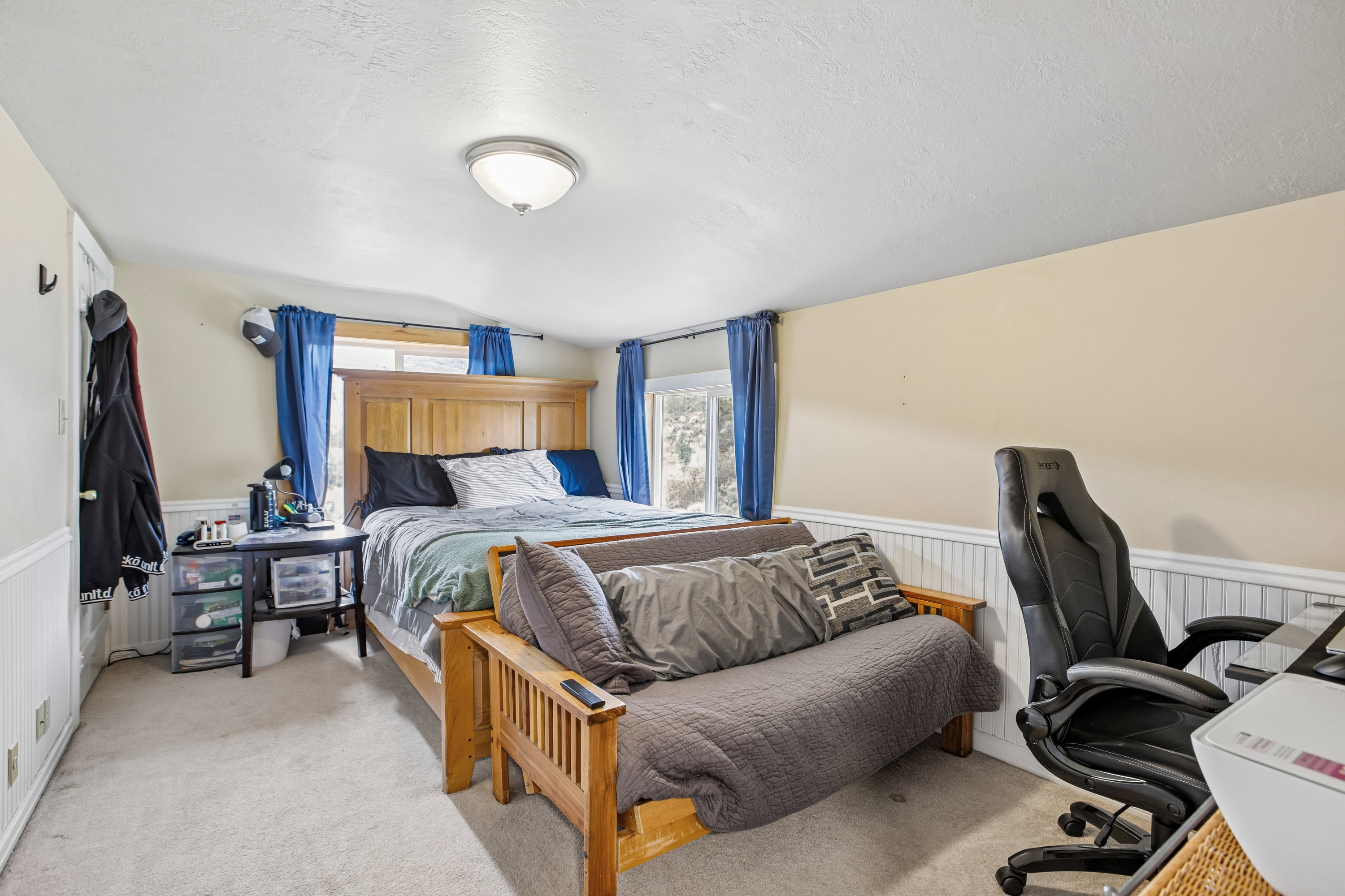 Bedroom featuring wainscoting, light colored carpet, and a desk