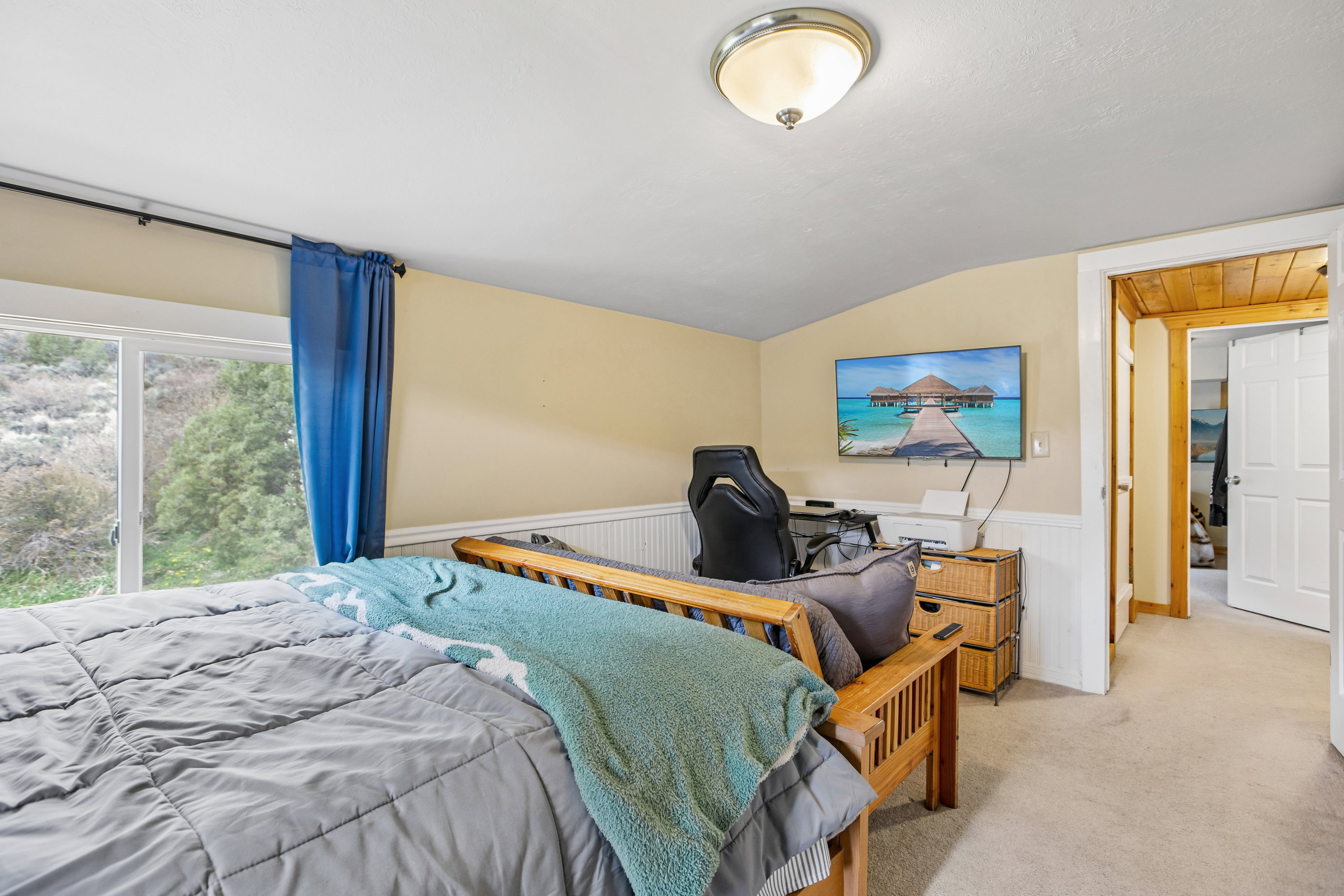 Carpeted bedroom featuring wainscoting and vaulted ceiling