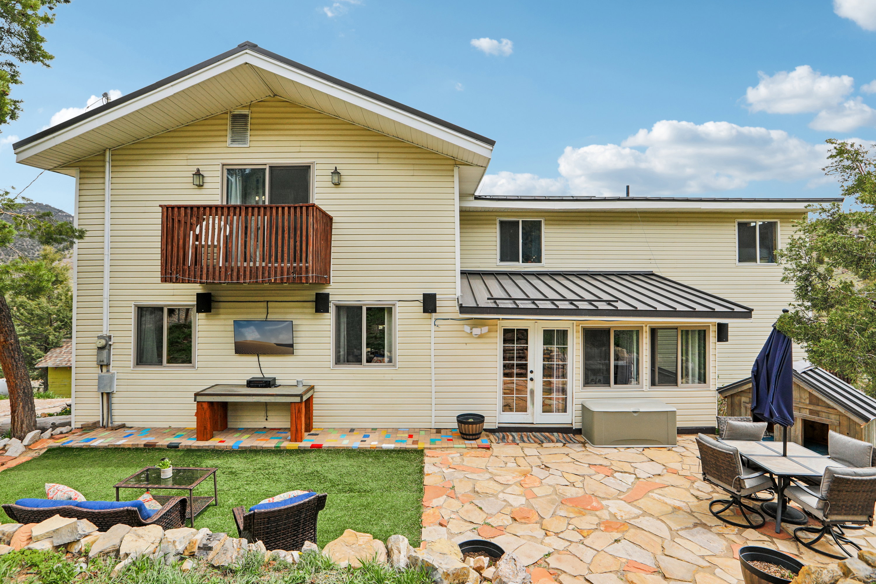 Back of property featuring a standing seam roof, a patio area, a balcony, outdoor dining area, and french doors