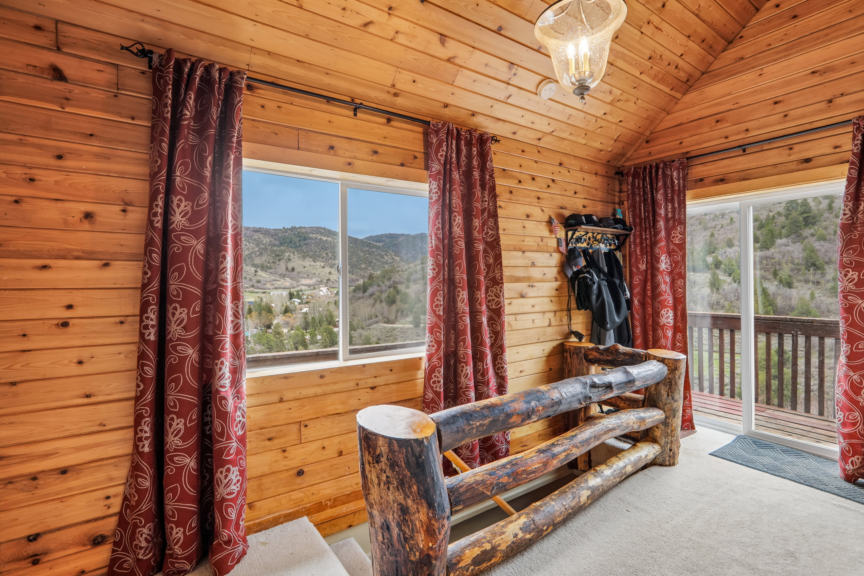 Sitting room with a mountain view, wood walls, carpet flooring, and a vaulted wood ceiling