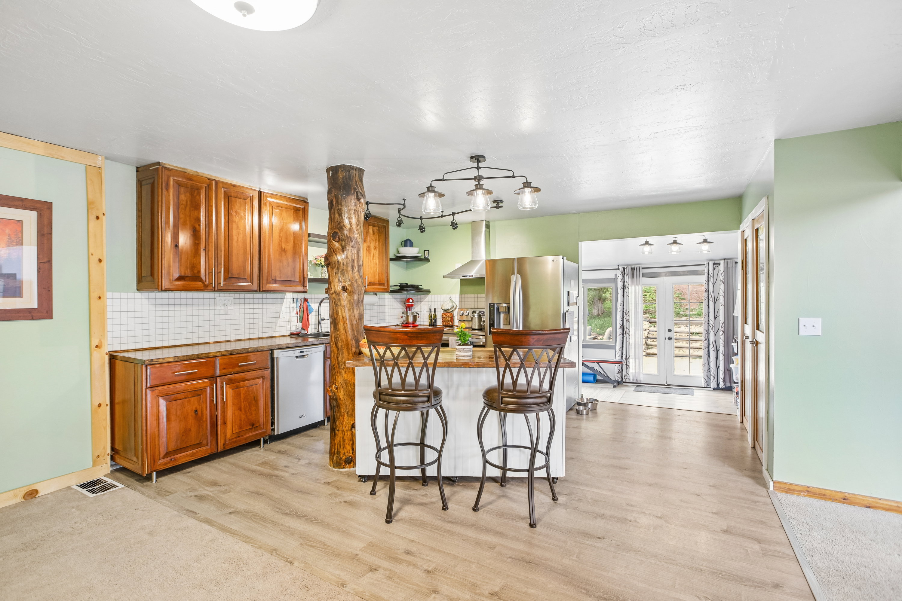 Kitchen with wood finish cabinetry, decorative backsplash, a kitchen island, french doors, and dishwasher