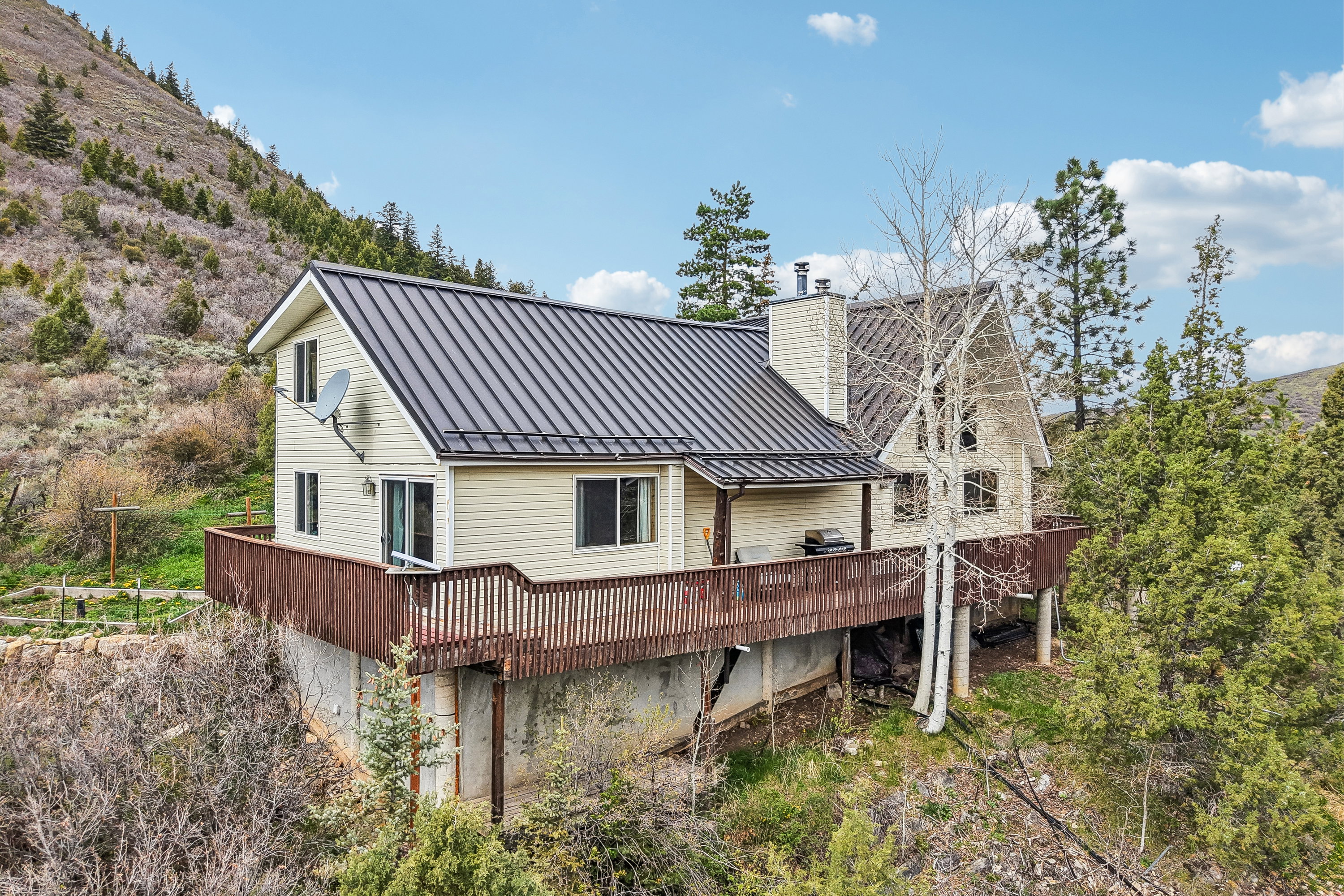 Back of property with a standing seam roof, a chimney, and a wooden deck
