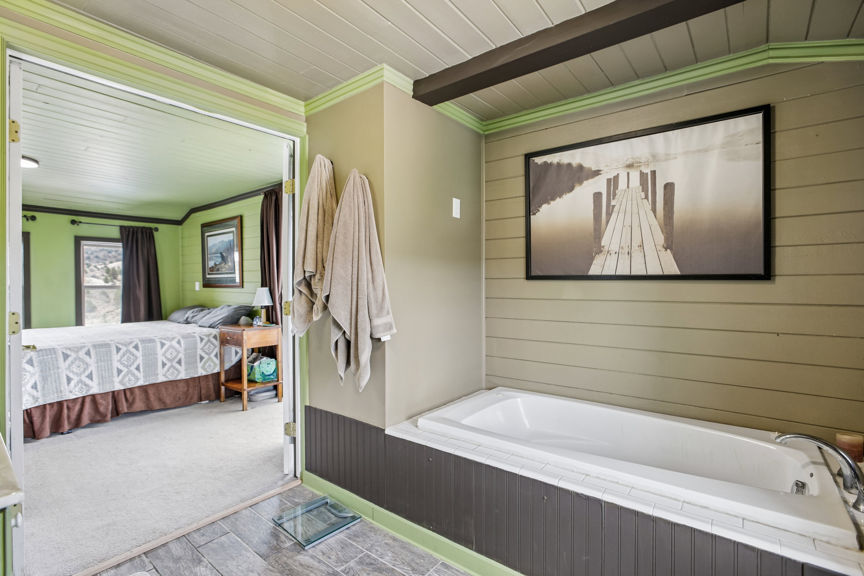Ensuite bathroom with wood walls, ornamental molding, a garden tub, and wooden ceiling
