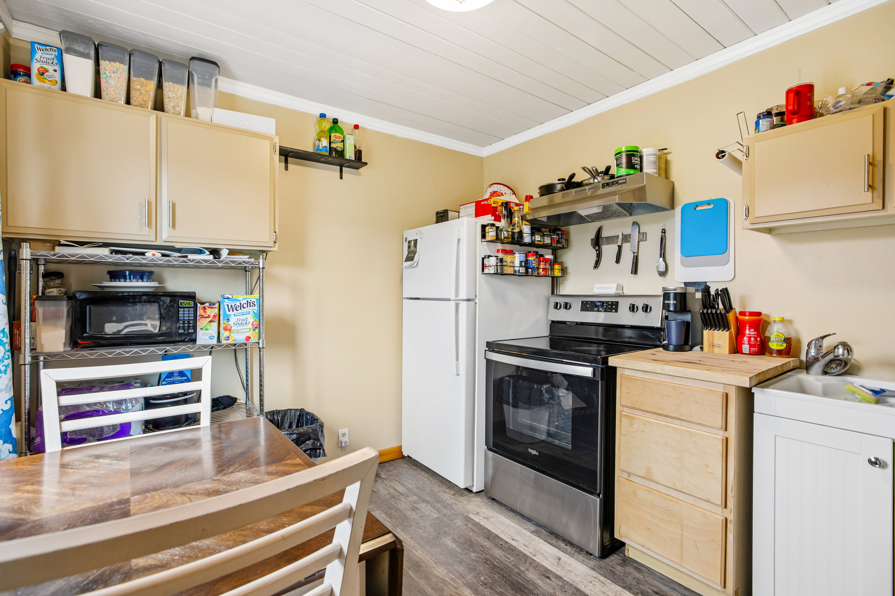 Kitchen with stainless steel electric stove, dark wood-style floors, ornamental molding, light wood finish cabinetry, and range hood