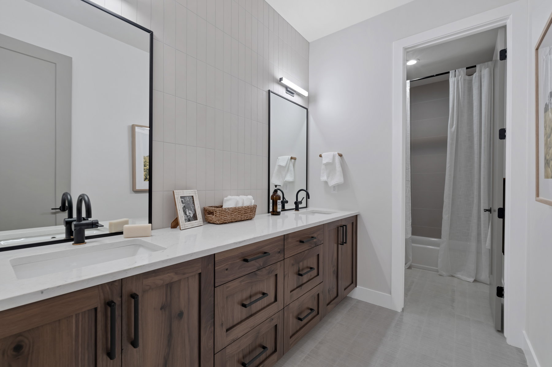 Bathroom with double vanity, shower / bath combo, and tile walls