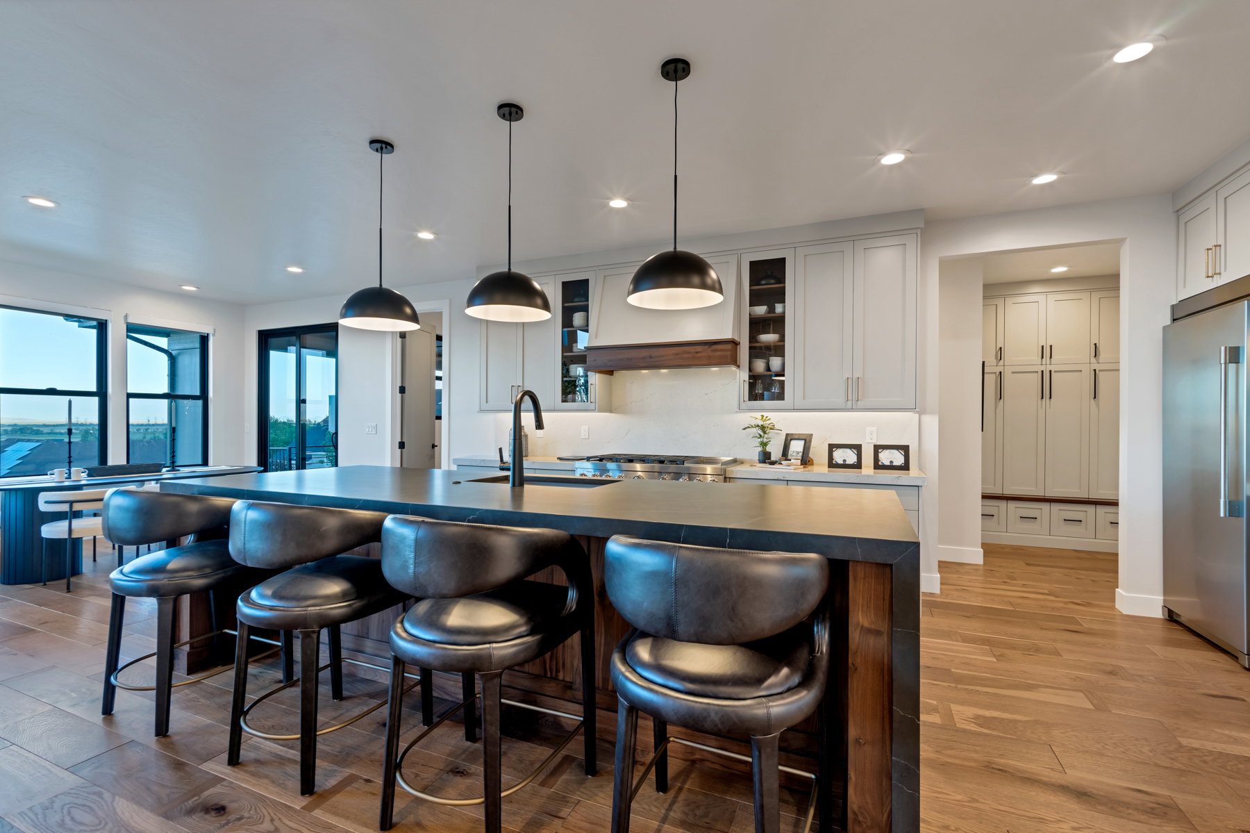 Kitchen featuring glass insert cabinets, high quality fridge, pendant lighting, light wood-style floors, and a breakfast bar