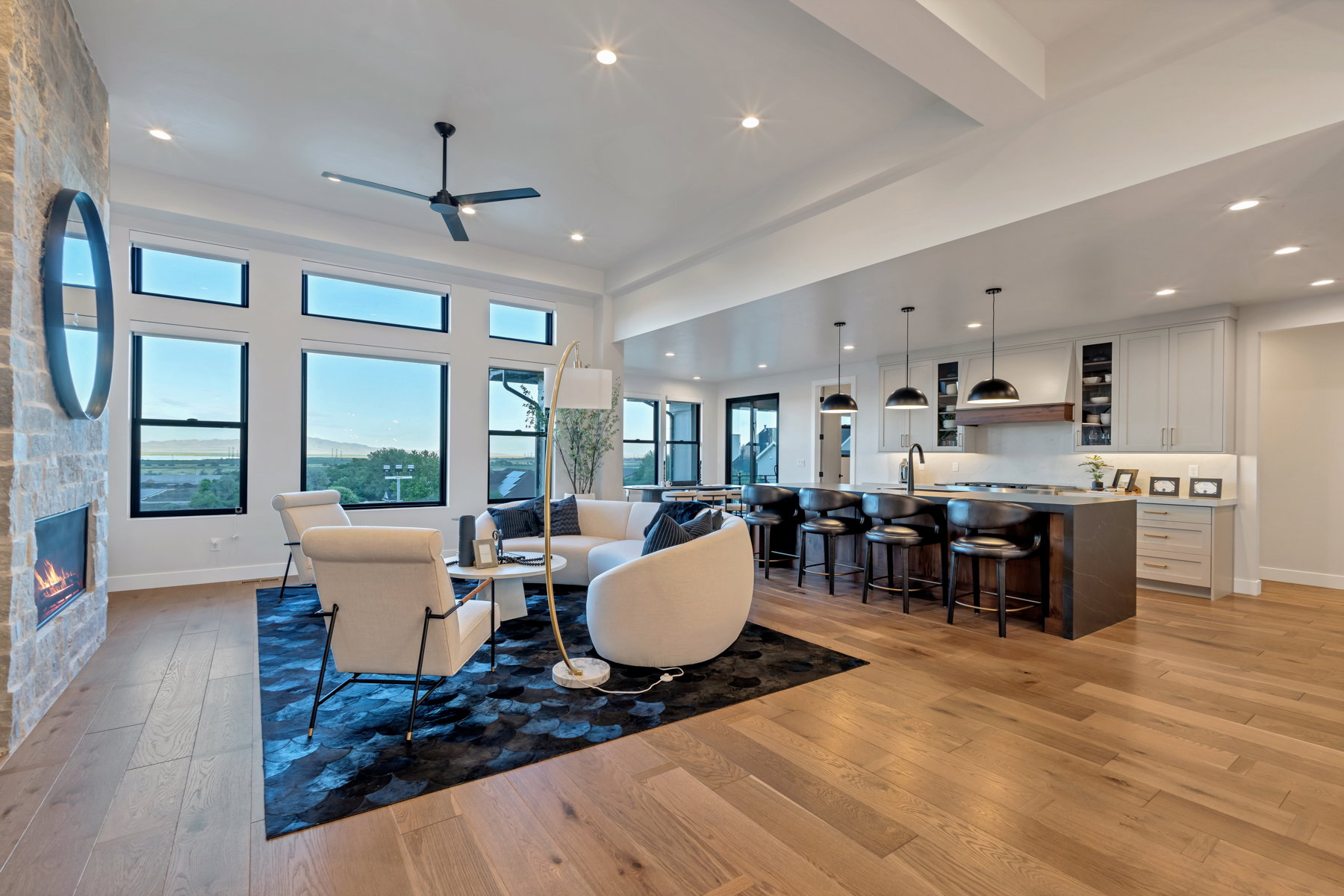Living area with light wood-type flooring, a fireplace, ceiling fan, a high ceiling, and recessed lighting