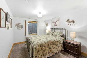 Bedroom featuring dark carpet and baseboards