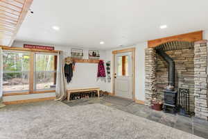 Mudroom with stone tile flooring, a wood stove, and recessed lighting