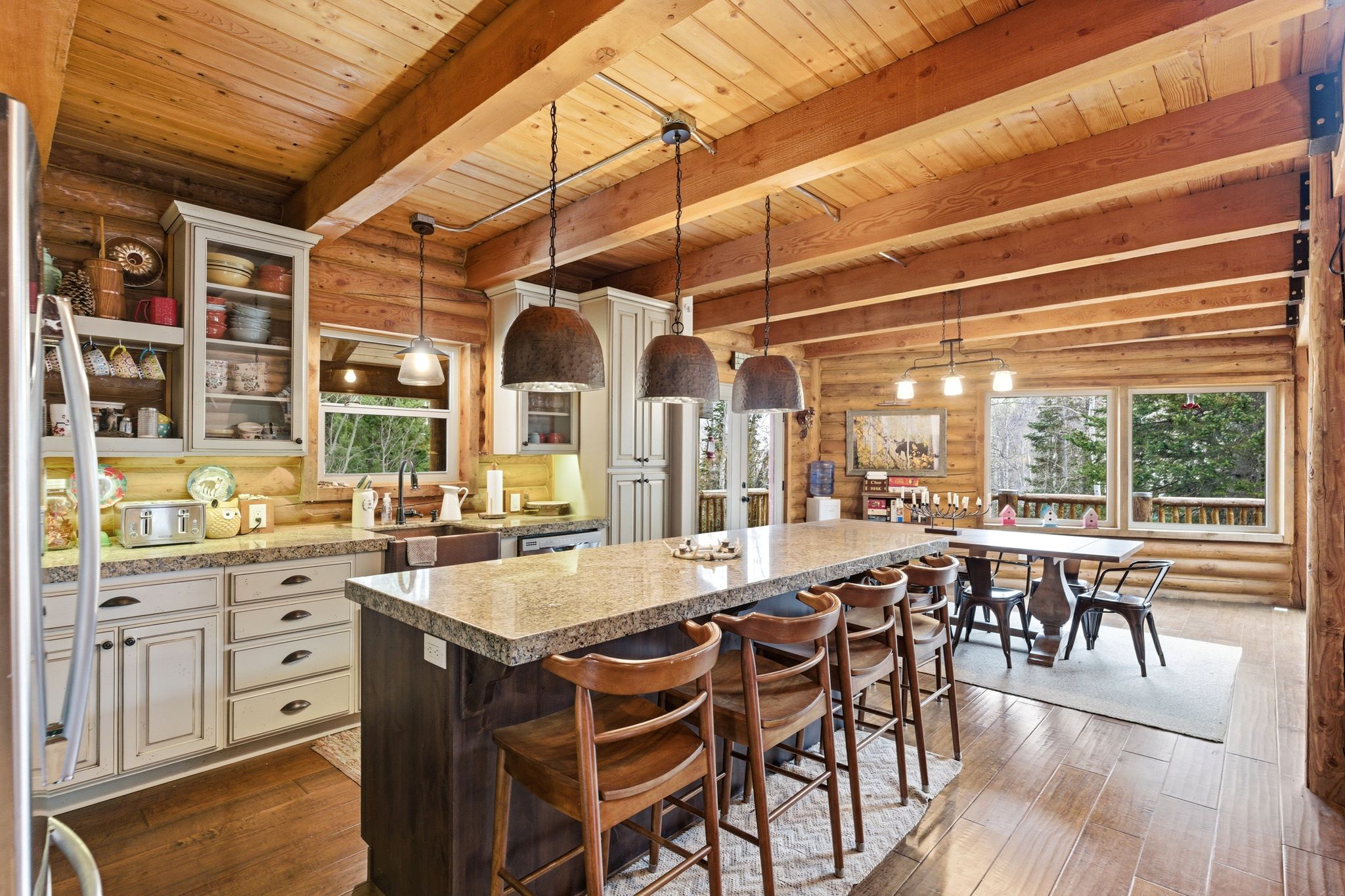 Kitchen featuring rustic walls, glass fronted cabinets, two tone cabinetry, pendant lighting, and dark wood-style flooring
