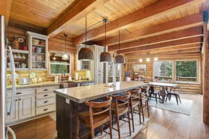 Kitchen featuring rustic walls, glass fronted cabinets, two tone cabinetry, pendant lighting, and dark wood-style flooring
