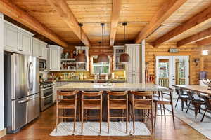 Kitchen featuring stainless steel appliances, french doors, dark wood-type flooring, rustic walls, and a wooden ceiling with exposed beams