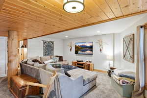 Carpeted living room featuring wood ceiling, wood walls, and recessed lighting