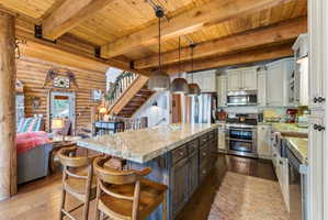 Kitchen with two tone color scheme, dark wood-type flooring, stainless steel appliances, rustic walls, and a kitchen bar