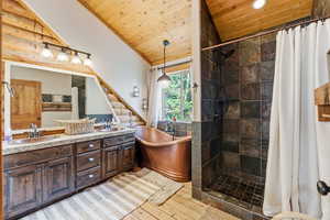 Bathroom featuring wooden ceiling, double vanity, a shower stall, light wood-style floors, and a soaking tub