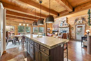 Kitchen with a kitchen bar, rustic walls, dark wood finish cabinetry, dark wood finished floors, and decorative light fixtures
