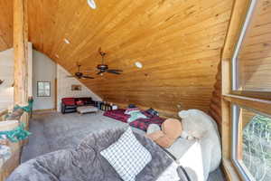 Carpeted bedroom featuring a vaulted wood ceiling and wood walls