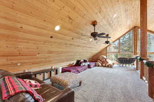 Sitting room with wooden ceiling, carpet flooring, rustic walls, and a ceiling fan