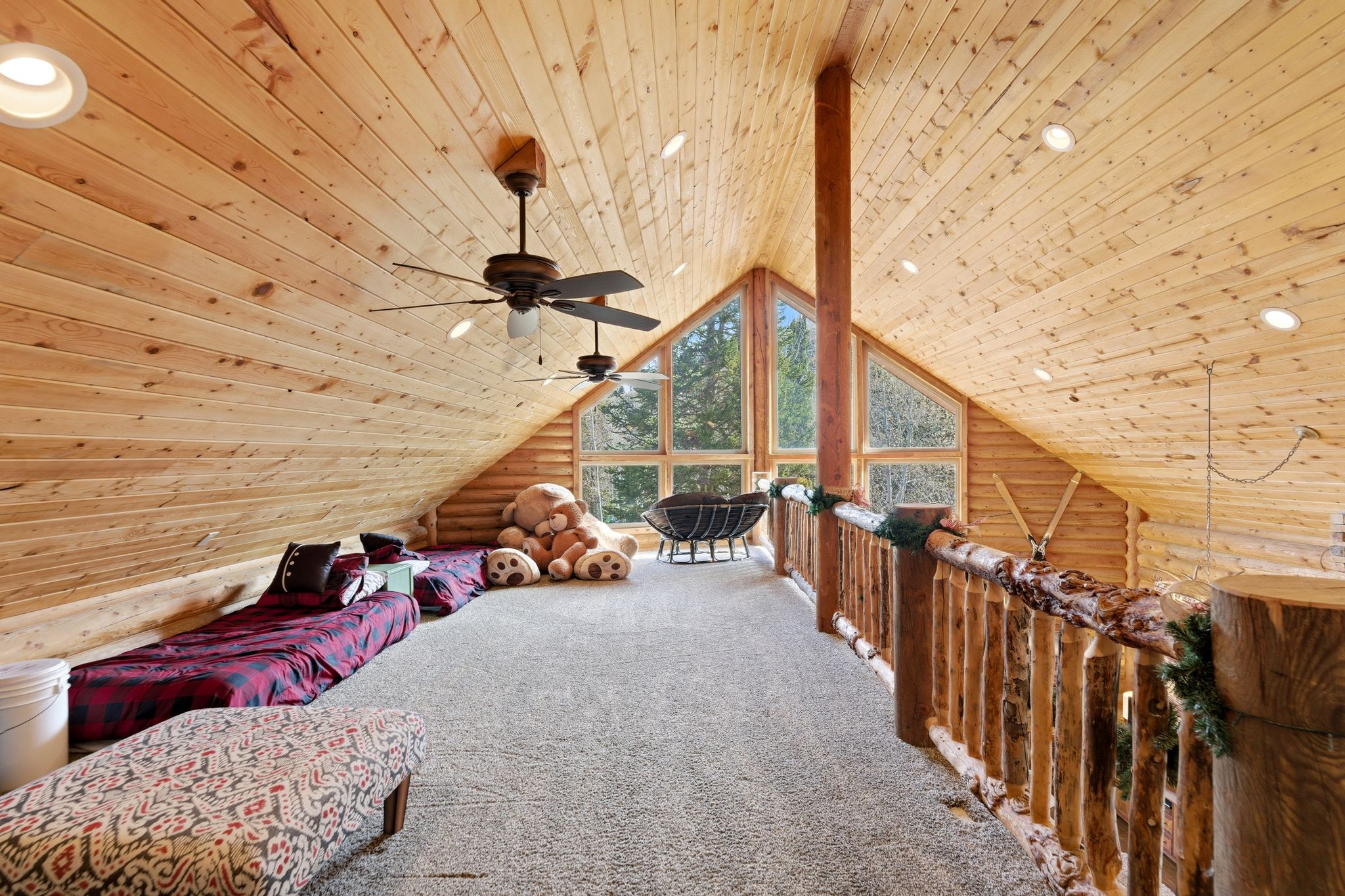 Living area featuring log walls, wooden ceiling, carpet flooring, and a ceiling fan