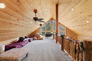 Living area featuring log walls, wooden ceiling, carpet flooring, and a ceiling fan