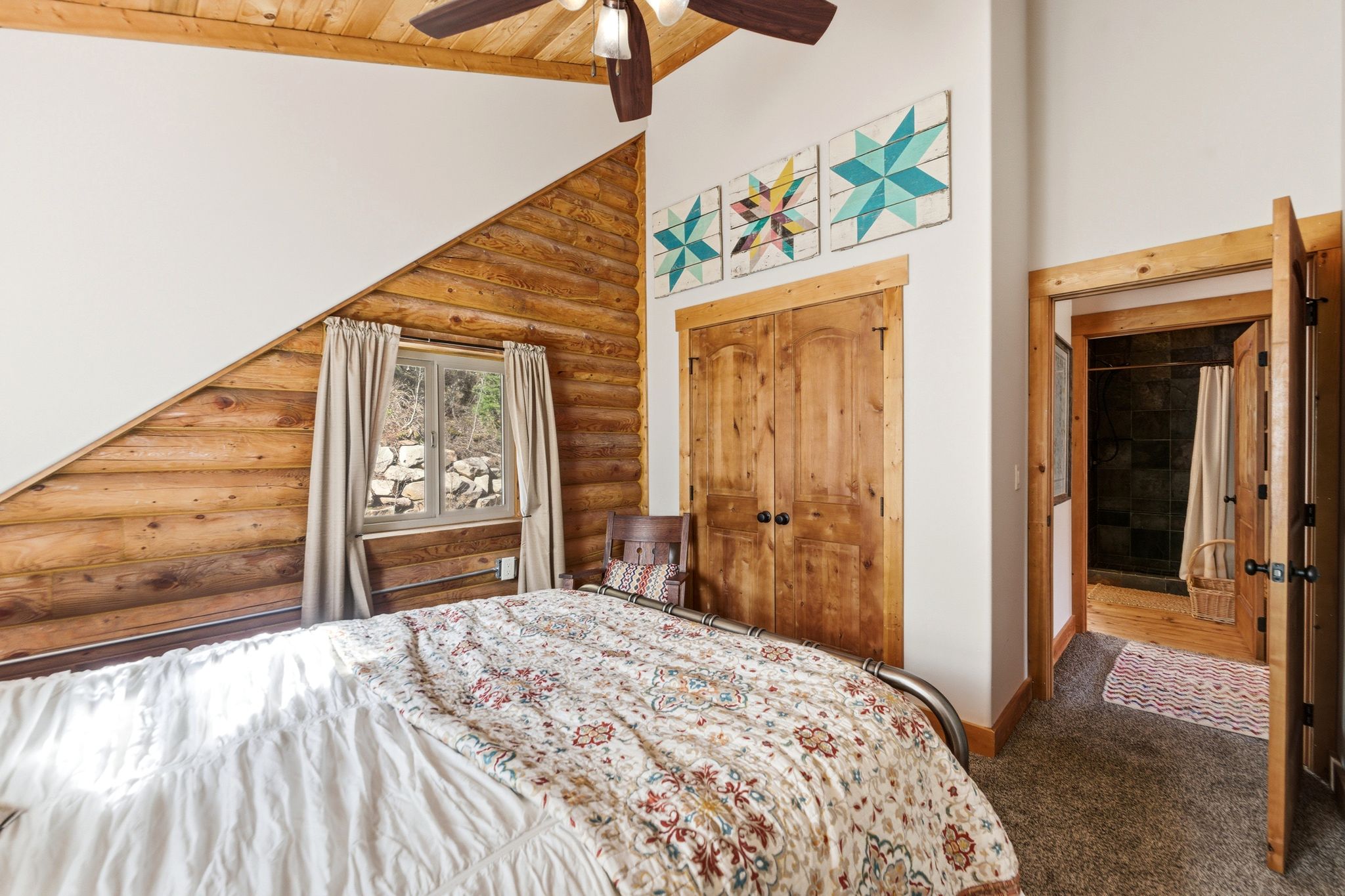 Bedroom featuring log walls, dark carpet, a closet, a ceiling fan, and a vaulted wood ceiling