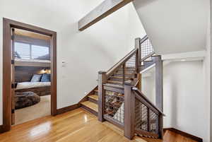 Staircase with wood finished floors and a high ceiling