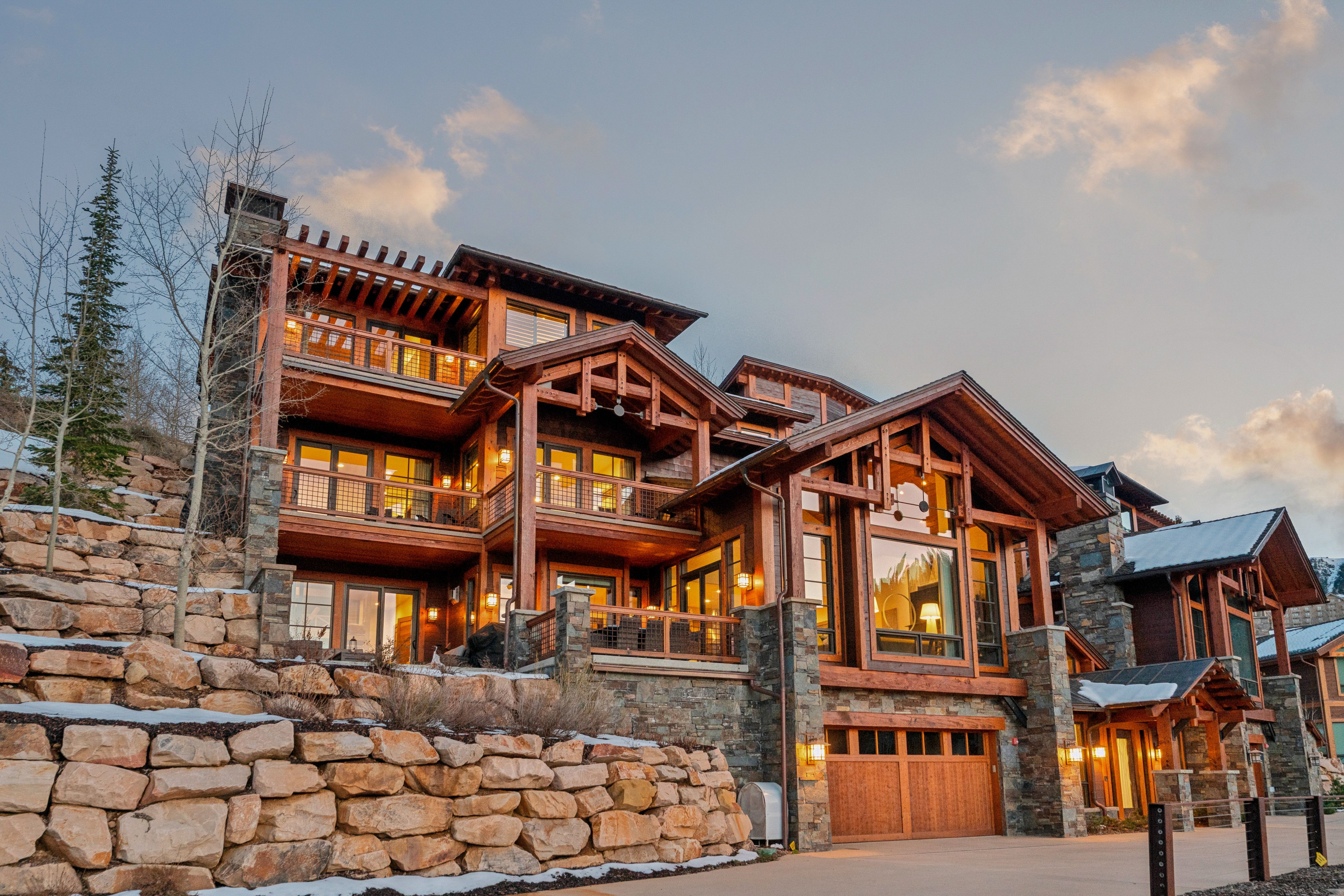 View of front of home with a balcony, stone siding, an attached garage, and driveway