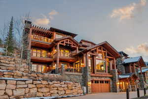 View of front of home with a balcony, stone siding, an attached garage, and driveway
