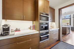 Kitchen with dark wood finished floors, modern cabinets, double oven, and wood finish cabinetry