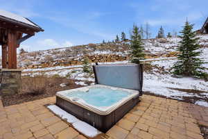 Snow covered patio featuring a patio and an outdoor hot tub