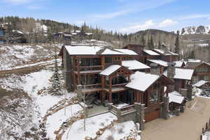 Snow covered house with an attached garage, concrete driveway, and a residential view