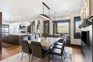 Dining room with dark wood-style floors, a fireplace, and recessed lighting