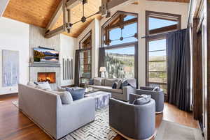 Living area with a high wooden beamed ceiling, a tiled fireplace, and wood finished floors