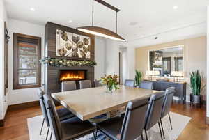 Dining space with wood finished floors, a large fireplace, and recessed lighting