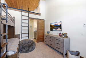 Sitting room featuring a barn door, a high wood ceiling, and light carpet