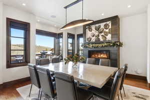 Dining room with wood finished floors, healthy amount of natural light, a large fireplace, and recessed lighting