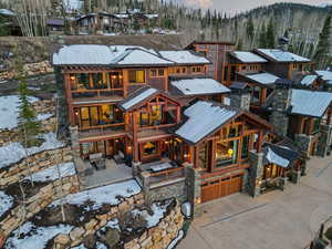 View of front facade featuring a balcony, driveway, stone siding, an attached garage, and a residential view