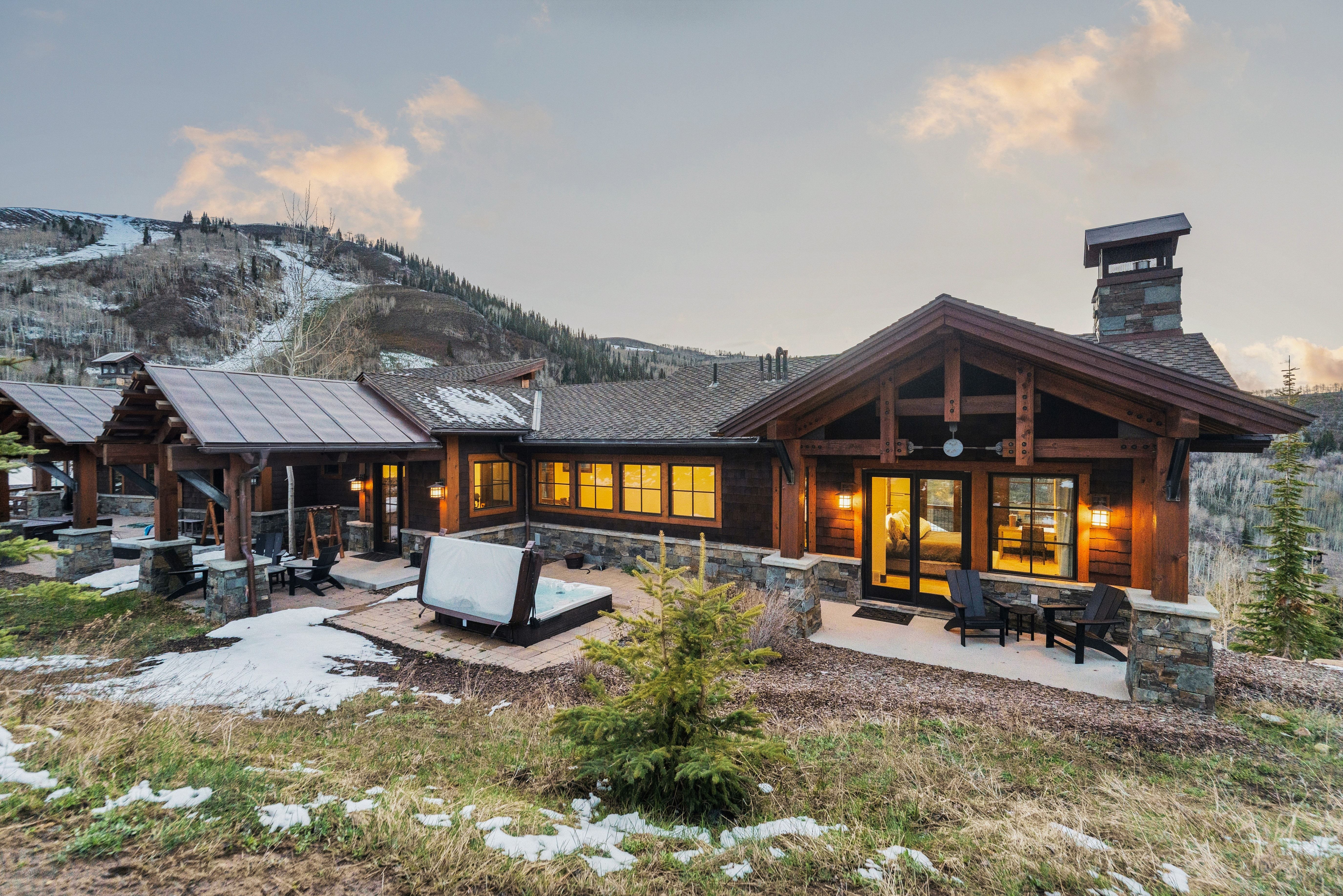 Back of property at dusk featuring a patio area, a chimney, solar panels, and stone siding
